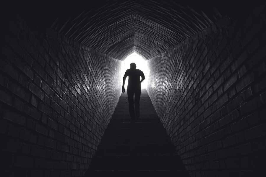 Person geht eine Treppe nach oben zum hellen Ausgang